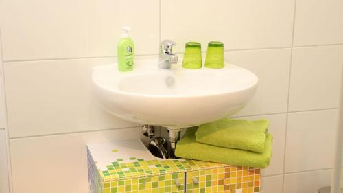 a bathroom with a sink and green towels on a box at Fewo Art City-Studio Kassel 3, modern, ruhig, citynah, kostenfreie Parkplätze, großer Balkon, voll ausgestattet in Vellmar