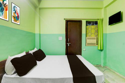 a bedroom with a white bed with green walls at Hotel O Raj in Dānāpur