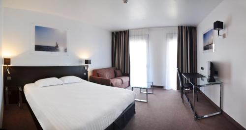 a hotel room with a large bed and a couch at Golden Tulip Pornic Suites- Appart Hotel in Pornic