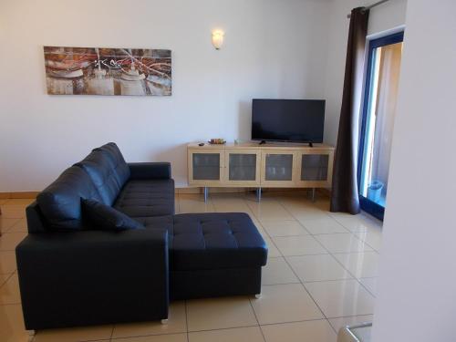 a living room with a couch and a flat screen tv at T1 e T2 Marina Albufeira apartments in Albufeira