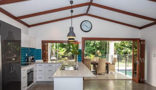 a kitchen with a clock on the wall at Cowrie Beach House Port Douglas in Port Douglas