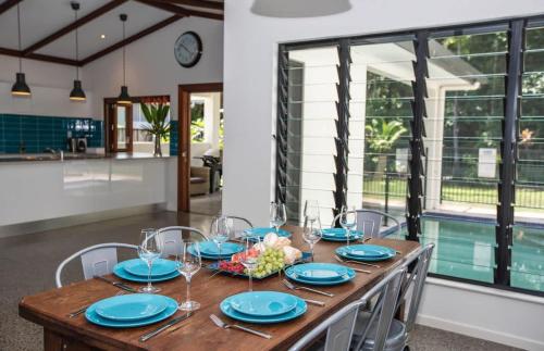 a dining room with a wooden table with wine glasses at Cowrie Beach House Port Douglas in Port Douglas