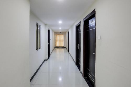 a hallway with black doors and a white tile floor at Collection O Lotus Grand in Hyderabad