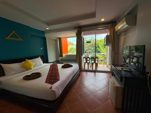 a bedroom with a bed and a television and a balcony at LAY TONG BEACH HOTEL Patong in Patong Beach