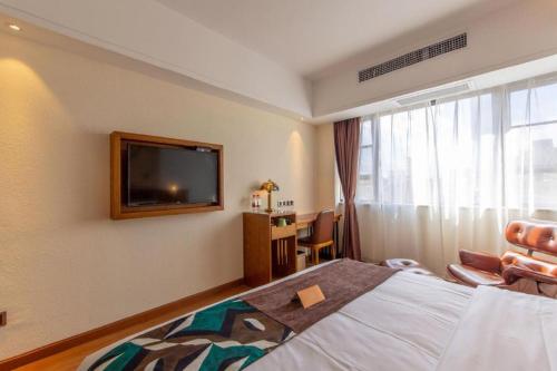 a hotel room with a bed and a flat screen tv at James Joyce Coffetel Kunming Railway Station Huancheng Nan Road Metro Station in Kunming