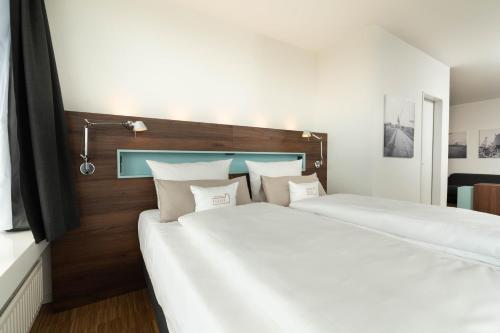 two beds in a room with white sheets at Hotel Alte Werft in Papenburg