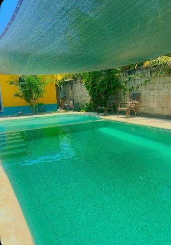 a large swimming pool with a green umbrella over it at Casa el Marinero in Monterrico