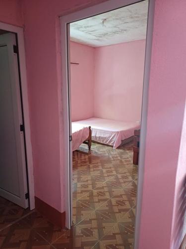 a pink room with a bed and a mirror at Casa el Marinero in Monterrico