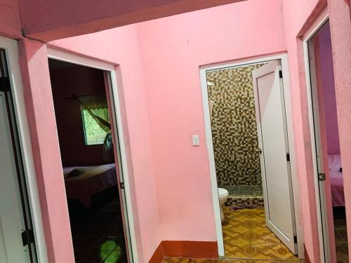 a bathroom with a pink wall and a toilet at Casa el Marinero in Monterrico