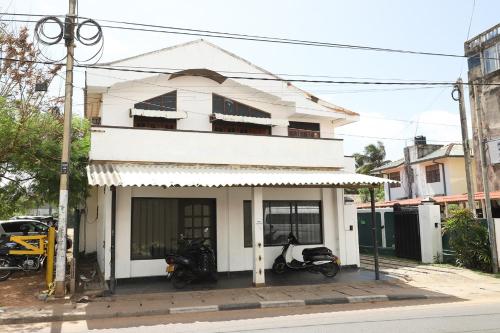 una casa blanca con dos motos estacionadas frente a ella en Landy Beachscape Hotel & Restaurant, en Negombo