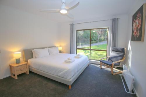 una camera da letto con un letto, una sedia e una finestra di Platypus Bend a Bright