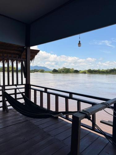 a hammock sitting on a dock next to the water at Namknong view in Don Det