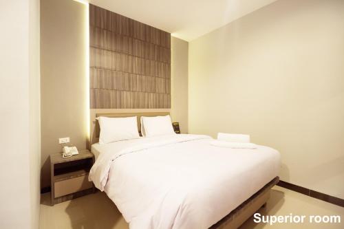 a bedroom with a white bed with a wooden headboard at Holitel Hotel in Pekanbaru