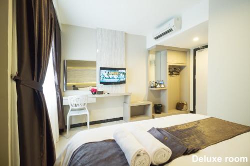 a bedroom with a bed and a desk with a television at Holitel Hotel in Pekanbaru