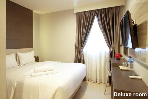 a hotel room with a bed and a window at Holitel Hotel in Pekanbaru