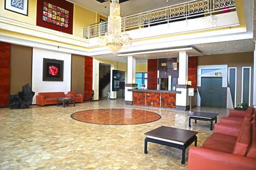 a large lobby with red furniture and a chandelier at PLUM Prestige Hotel Juanda in Kalangan