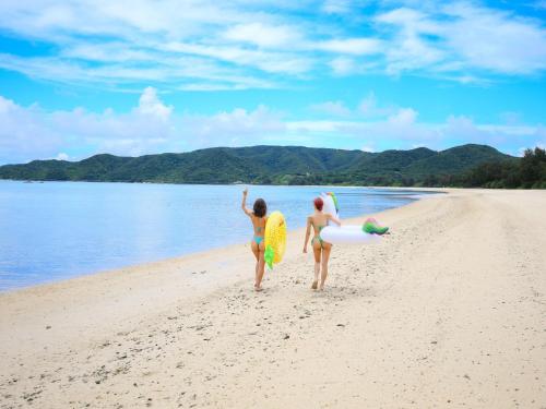 two girls walking on the beach with their surfboards at Le GRAND BLEU - Vacation STAY 31718v in Akaoki