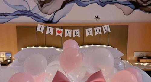 a bed with balloons and a sign that says hellomitemite at Venus Royal Hotel Nanning East High-Speed Railway Station in Nanning