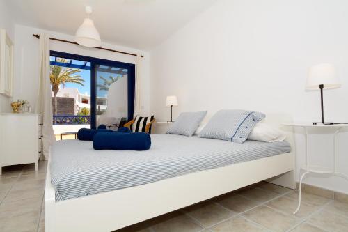 a white bed in a white room with a window at Villa Oasis in Playa Blanca