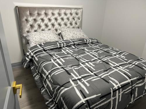 a bed with a black and white comforter and pillows at Modern 1-Bedroom Plus DenApartment in Markham with Free Parking in Markham