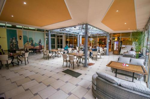 a restaurant with tables and chairs and people sitting at tables at Hotel Kralj Tomislav in Nova Gradiška