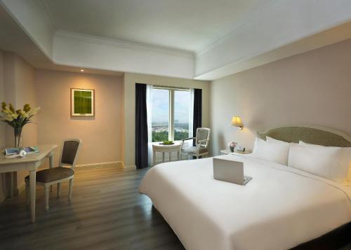 a hotel room with a large white bed and a desk at Berjaya Waterfront Hotel, Johor Bahru in Johor Bahru