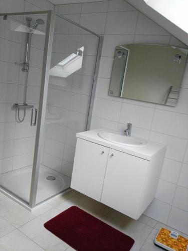 een witte badkamer met een wastafel en een douche bij Guesthouse SiSa in Veurne