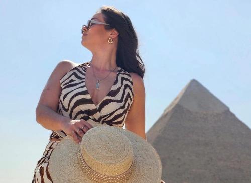a woman wearing a straw hat standing in front of the pyramids at Pyramids Grand View Hotel in Cairo