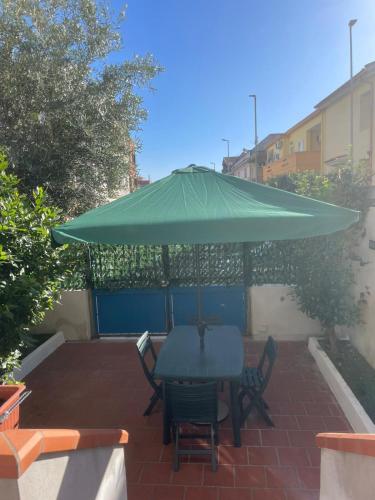a table and chairs under a green umbrella on a patio at Appartamento Numa Sardegna in Monserrato