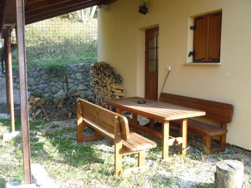 una mesa de madera y un banco frente a una casa en Holiday home Lokovec 31 - Rojčeva domačija, en Čepovan
