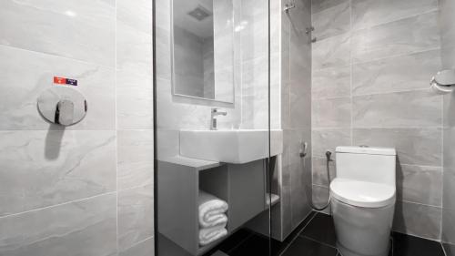 a white bathroom with a toilet and a sink at Amansari Hotel Nusajaya in Nusajaya
