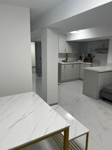 an empty kitchen with white cabinets and a table at Modern 1-Bedroom Plus DenApartment in Markham with Free Parking in Markham