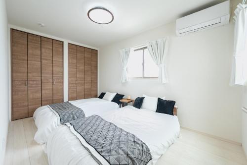 two beds in a bedroom with white walls at Ishigaki Island villa KURO in Ishigaki Island