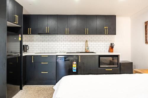 a kitchen with black cabinets and a stove top oven at Lakeside Bliss, Perfect Location Guesthouse in Wendouree