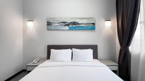 a bedroom with a bed with white sheets and pillows at Amansari Hotel Nusajaya in Nusajaya