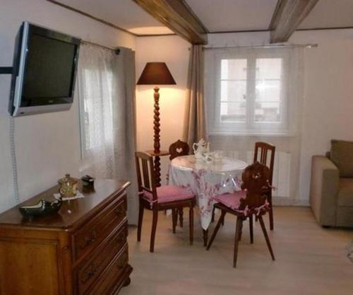 a living room with a table and chairs and a television at Gite du Marché d'Elsa in Kilstett