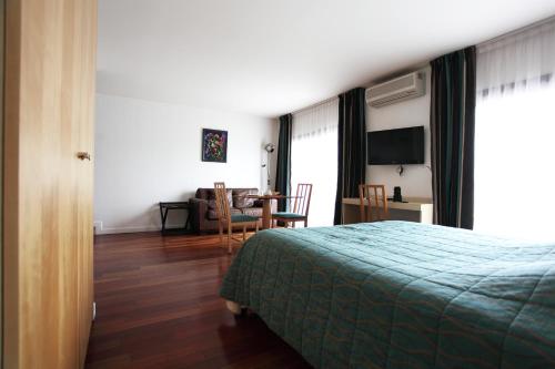 1 dormitorio con 1 cama y sala de estar con mesa en Hôtel la Scala, en Pithiviers