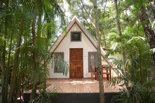 a small white house in the middle of trees at Temple Garden Palolem in Canacona