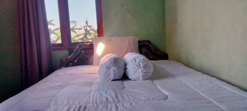 a bed with two pillows on it with a window at Molas Homestay 