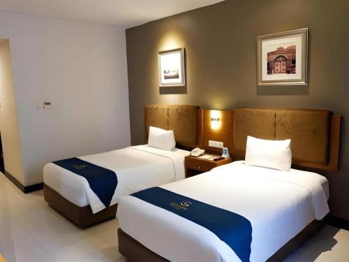 a hotel room with two beds in a room at Grage Hotel Cirebon in Cirebon