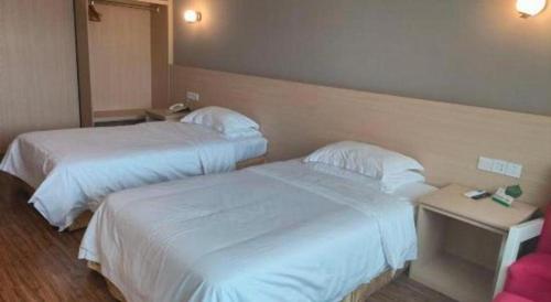 two beds in a hotel room with white sheets at Grand Nest Hotel (Tang Jia Wan Beach) in Zhuhai