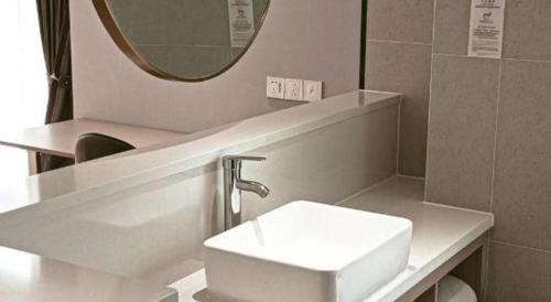 a bathroom with a white sink and a mirror at Grand Nest Hotel (Tang Jia Wan Beach) in Zhuhai