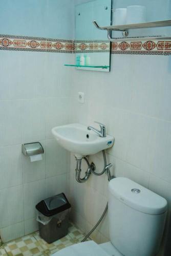 a white bathroom with a sink and a toilet at Uma Taman House in Ubud