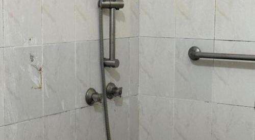 a shower with a hose in a white tile wall at Lai Ming Hotel Cosmoland in Singapore