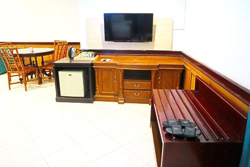 a living room with a flat screen tv and a bench at PLUM Prestige Hotel Juanda in Kalangan