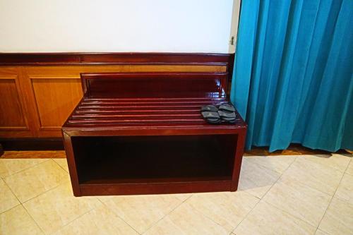 a wooden bench with a pair of shoes on it at PLUM Prestige Hotel Juanda in Kalangan