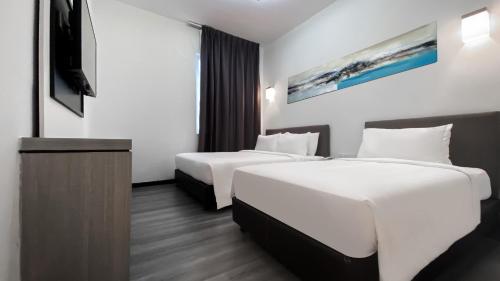 a hotel room with two beds and a tv at Amansari Hotel Nusajaya in Nusajaya