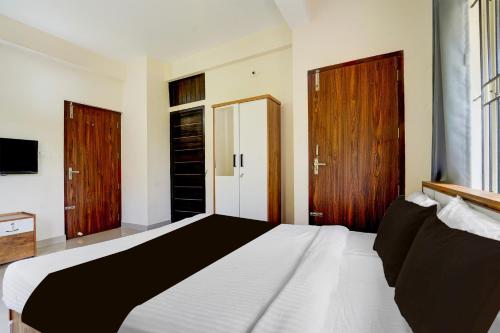 a bedroom with a large white bed with wooden doors at Super Collection O Calicut Near Calicut Medical College in Kakkayam