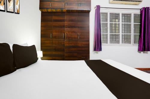 a bedroom with a bed with purple curtains and a window at Hotel O Kogilu Bus Terminal Formerly Peaceful Stay in Yelahanka