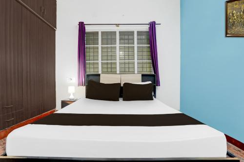 a bedroom with a large white bed with purple curtains at Hotel O Kogilu Bus Terminal Formerly Peaceful Stay in Yelahanka